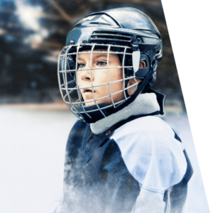 A young boy looks off screen. He is wearing his hockey gear.