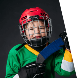 A child hockey player wears a green jersey and red helmets, holds hockey stick blade.